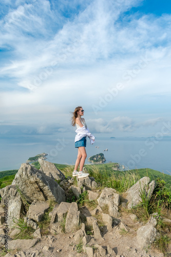 Girl in summer clothes on the top of the mountain near the sea