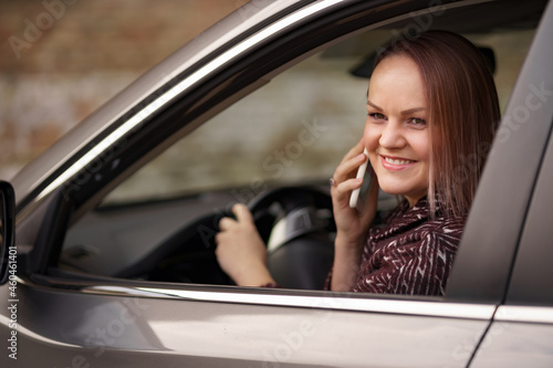 Woman In Car Talking On Mobile Phone Whilst Driving. Attractive woman uses smart phone while driving.
