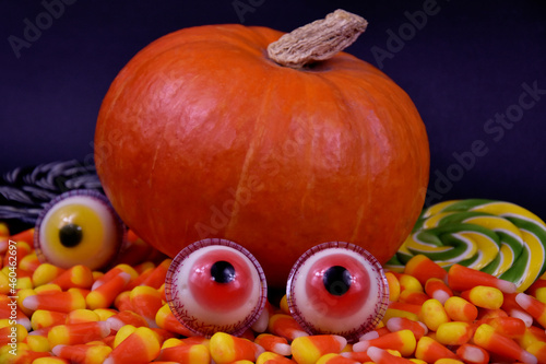 Halloween pumpkin with spooky eyes and candy corn candies stock images. Decorative halloween pumpkin and sweets on a black background stock photo