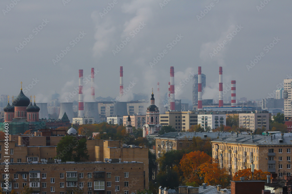 City panorama with the domes of the cathedrals in the Donskoy Monastery, the roofs of nearby houses and the pipes of thermal power plant on an sunny autumn day.