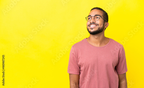 Young latin man isolated on yellow background thinking an idea while looking up