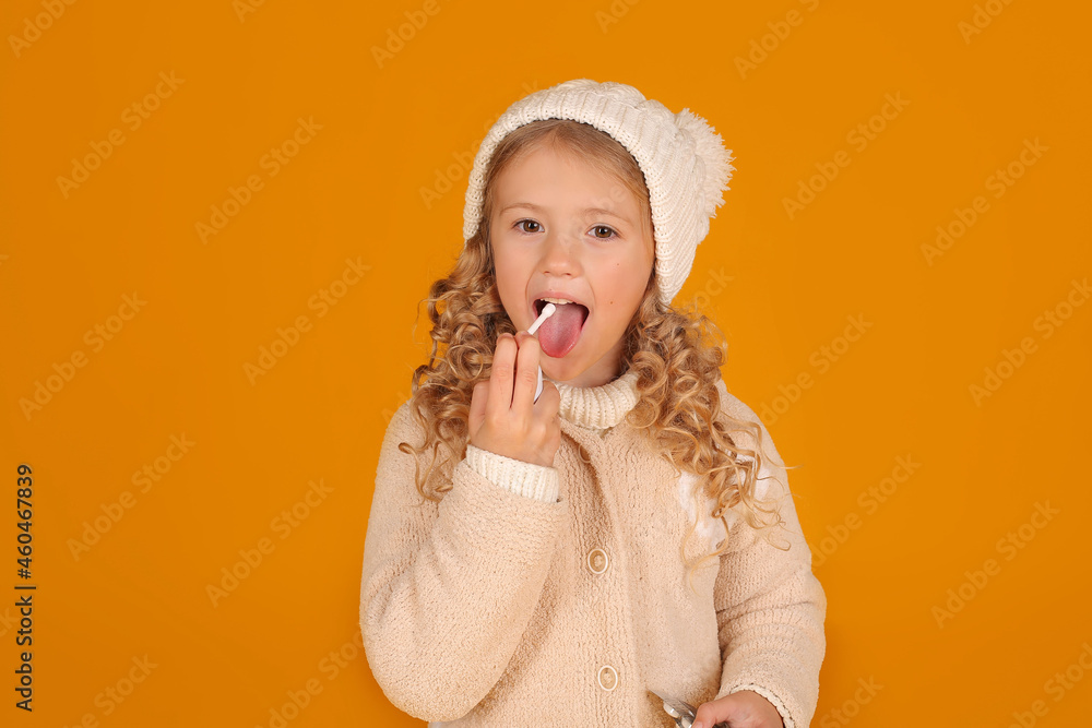 a blonde girl in a knitted jacket and a winter knitted hat pours cold medicine into her mouth a blonde girl in a knitted jacket and a winter knitted hat pours cold medicine into her mouth