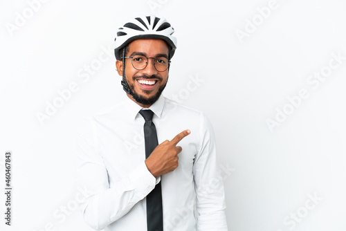 Young business latin man holding a bike helmet isolated on white background pointing to the side to present a product