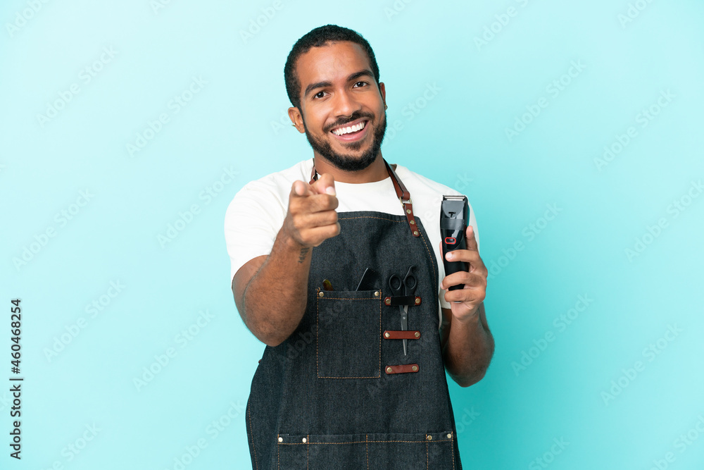 Fototapeta premium Young hairdresser latin man isolated on blue background pointing front with happy expression