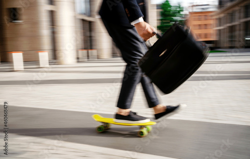 A blurry photo in motion. A businessman manager hurries to a meeting with colleagues  holds a briefcase and rides a skateboard.