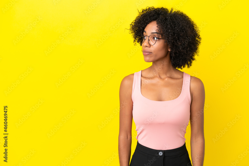 Young African American woman isolated on yellow background looking to the side Young African American woman isolated on yellow background looking to the side
