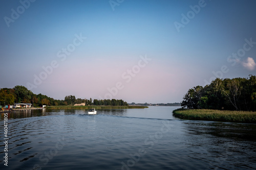 A small motorboat on Dziwna River, at harbour entrance in Dziwnow, Poland. Blue sky, background with copyspace. 