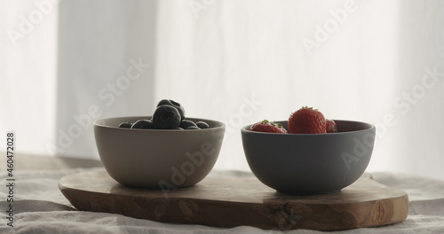 strawberries and blueberries in bowls on wood table
