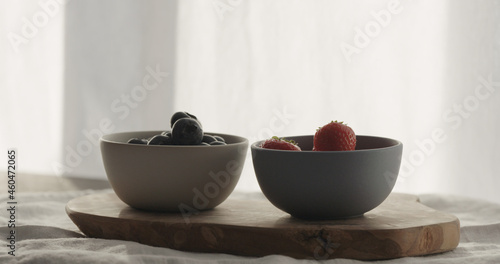 strawberries and blueberries in bowls on wood table