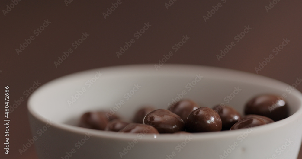 Fototapeta premium chocolate covered pistachios in white bowl on walnut table