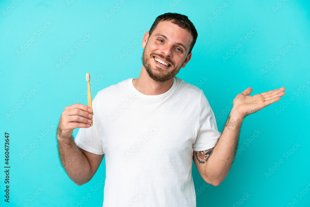 Young Brazilian man brushing teeth isolated on blue background with shocked facial expression Young Brazilian man brushing teeth isolated on blue background with shocked facial expression