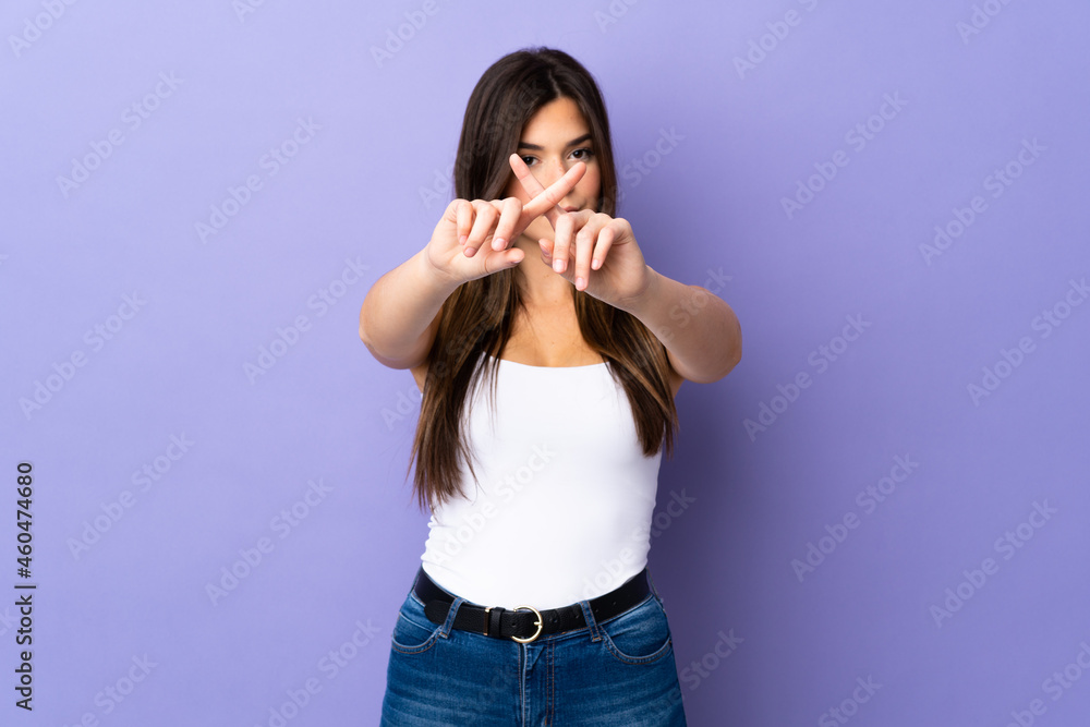 Teenager Brazilian girl over isolated purple background making stop gesture with her hand to stop an act Teenager Brazilian girl over isolated purple background making stop gesture with her hand to stop an act