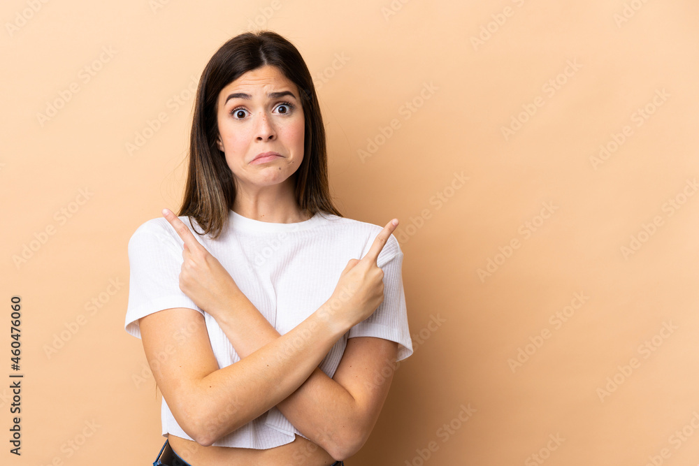 Teenager Brazilian girl over isolated background pointing to the laterals having doubts Teenager Brazilian girl over isolated background pointing to the laterals having doubts