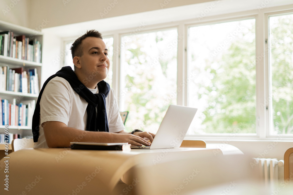 A new academic year at the university. A student at a desk studying at a college. A young man in the library of the Institute. Read an online book on a computer. A new academic year at the university. A student at a desk studying at a college. A young man in the library of the Institute. Read an online book on a computer.