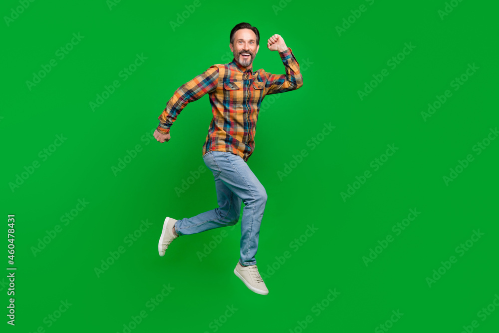 Full length body size view of attractive sporty lucky cheerful man jumping running isolated over bright green color background Full length body size view of attractive sporty lucky cheerful man jumping running isolated over bright green color background
