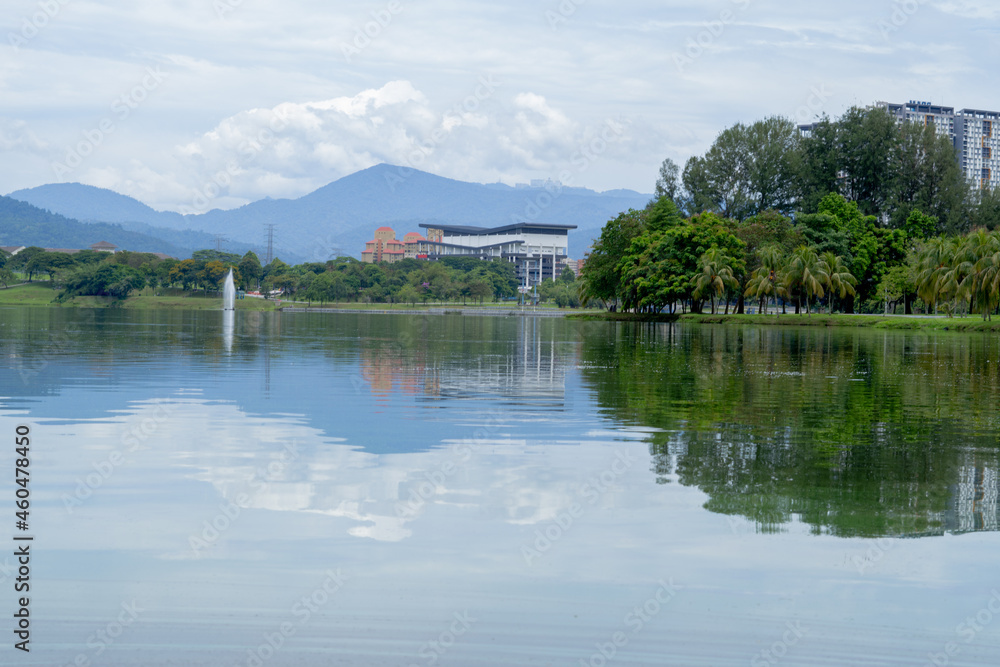 landscape shot of a lake in Kepong, Kuala Lumpur, Malaysia with reflection on the water, building and  the mountains in background. 