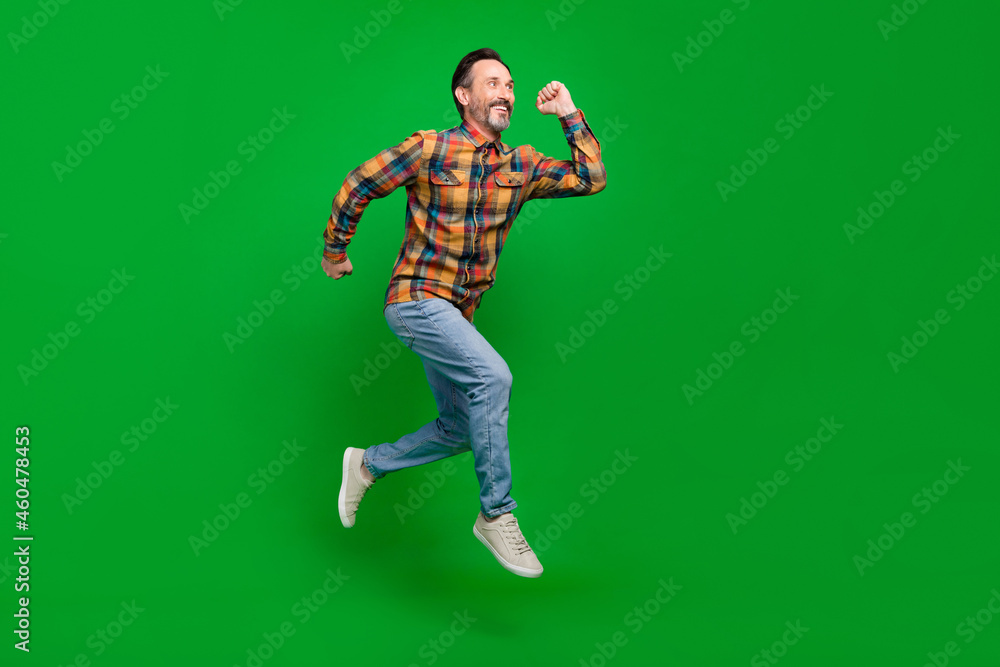 Full length body size view of attractive motivated cheerful man jumping running isolated over bright green color background