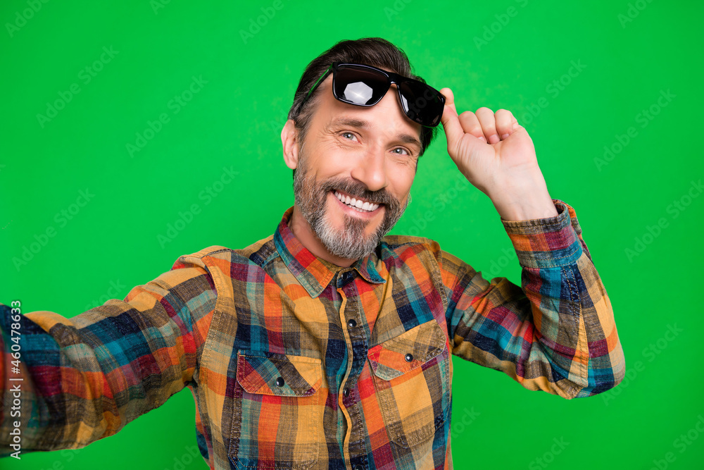 Self-portrait of attractive cheerful man touching specs posing good mood isolated over bright green color background Self-portrait of attractive cheerful man touching specs posing good mood isolated over bright green color background