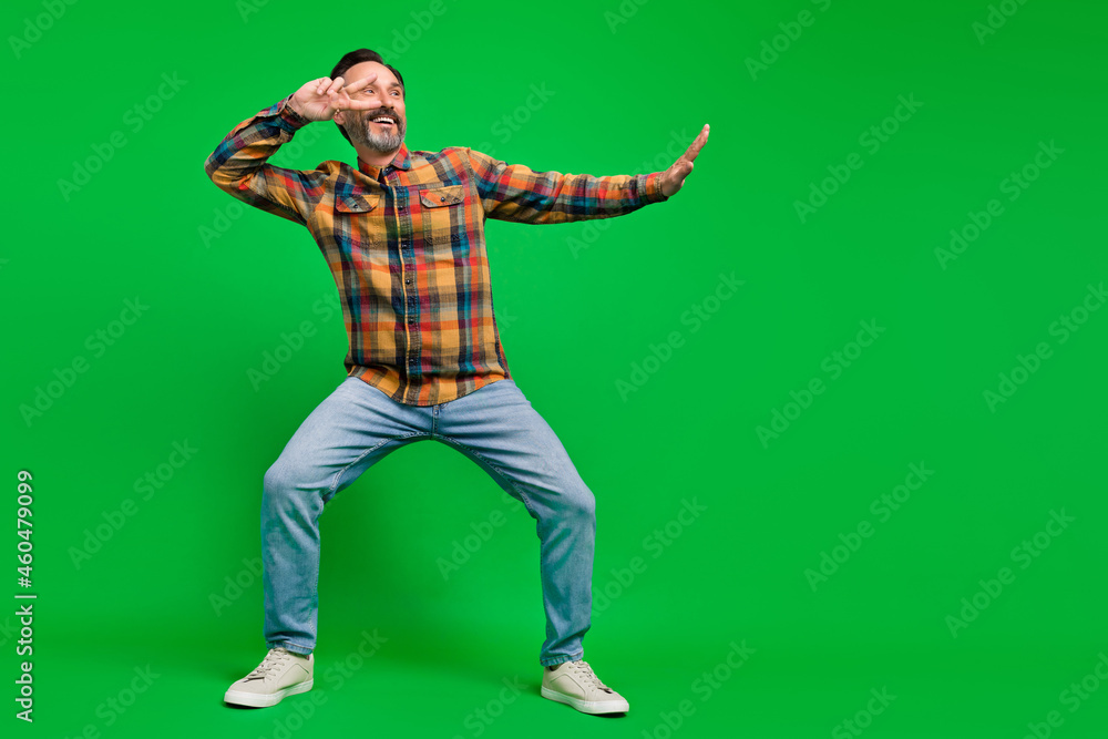 Full length body size view of attractive cheerful man dancing showing v-sign isolated over bright green color background Full length body size view of attractive cheerful man dancing showing v-sign isolated over bright green color background