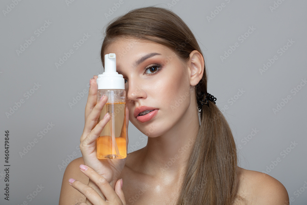 young woman with perfect skin carries out a wash. Gray background young woman with perfect skin carries out a wash. Gray background