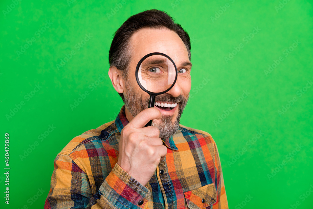Portrait of attractive cheerful amazed man holding looking glass find solution isolated over bright green color background Portrait of attractive cheerful amazed man holding looking glass find solution isolated over bright green color background