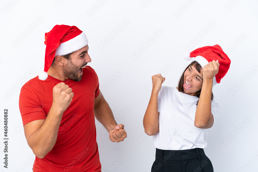 Young couple with christmas hat isolated on white background celebrating a victory in winner position Young couple with christmas hat isolated on white background celebrating a victory in winner position