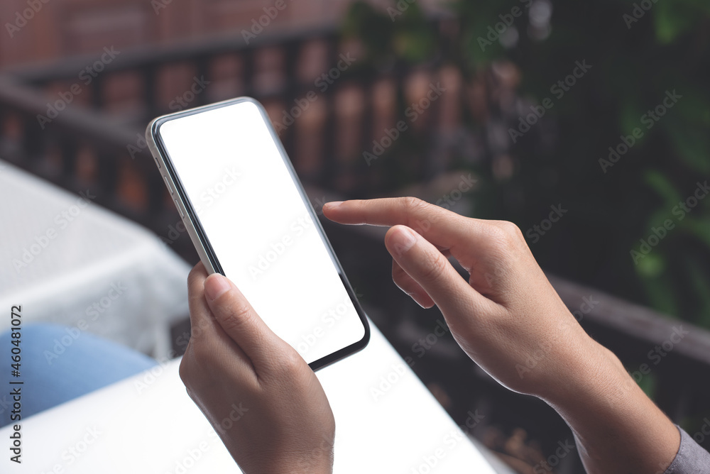 Cell phone mockup image blank white screen.  Woman hand holding, using mobile phone at home.