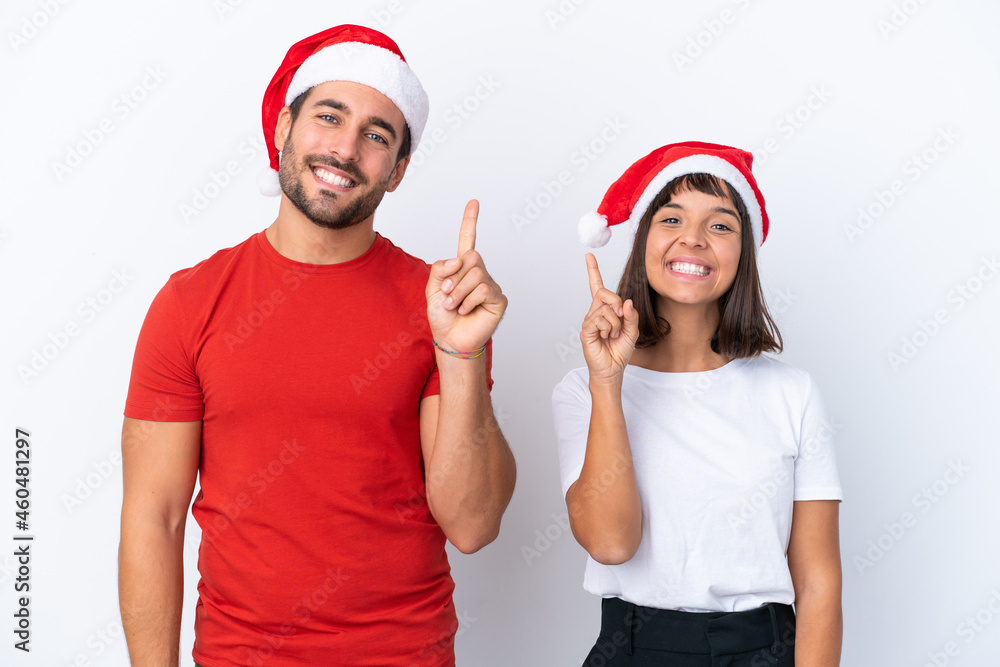 Young couple with christmas hat isolated on white background showing and lifting a finger in sign of the best Young couple with christmas hat isolated on white background showing and lifting a finger in sign of the best