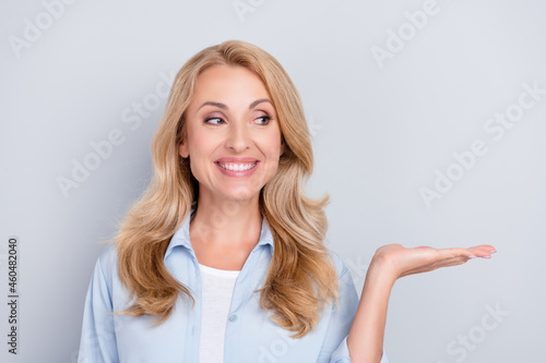 Photo of cheerful curious lady hand presenting empty space wear blue shirt isolated grey color background