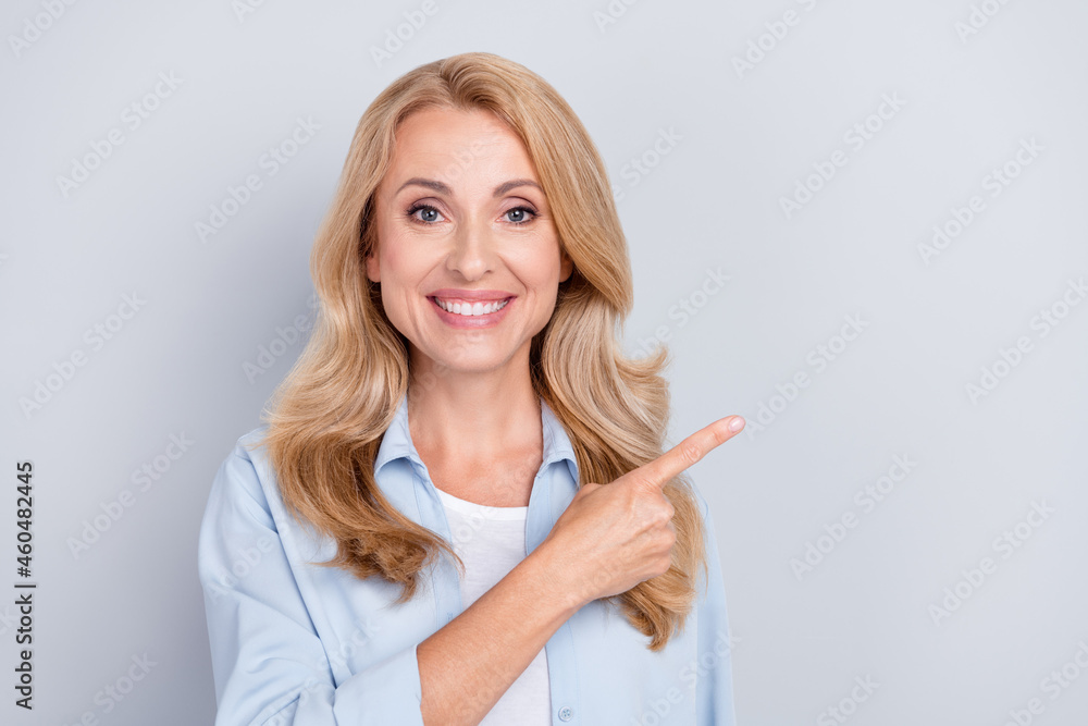 Photo of cheerful positive promoter lady direct finger empty space wear blue shirt isolated grey color background Photo of cheerful positive promoter lady direct finger empty space wear blue shirt isolated grey color background