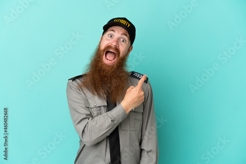 Redhead security man isolated on white background surprised and pointing side