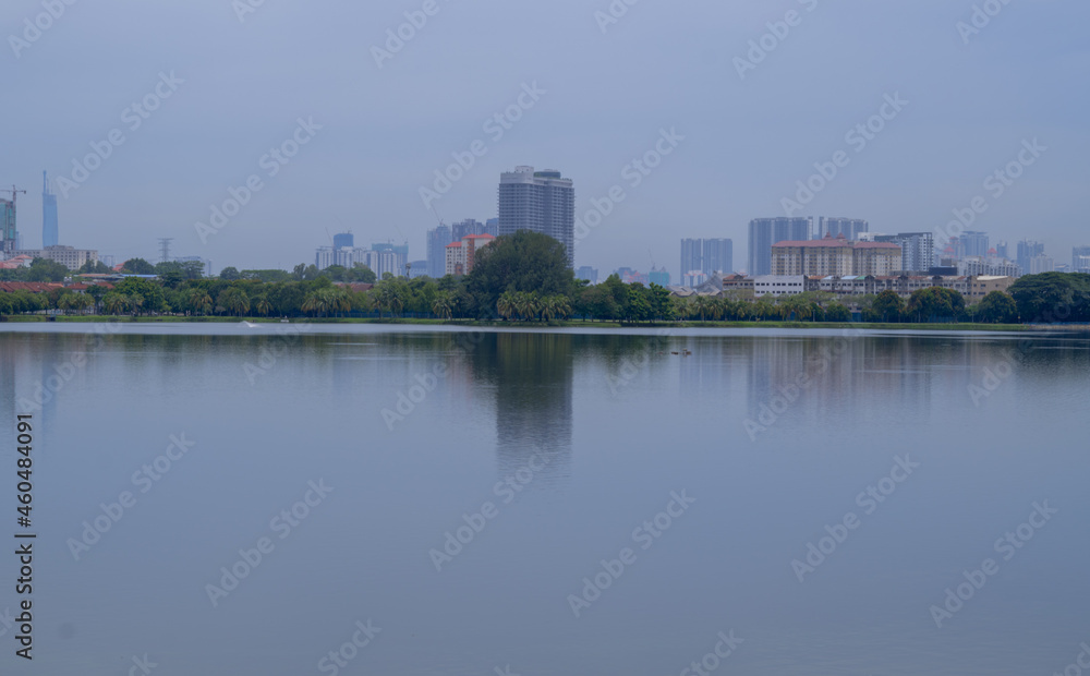 Beautiful city scape view of Kuala Lumpur city from the Kepong through the lake. Sunny day scene, reflecting on water and high buildings in background. 