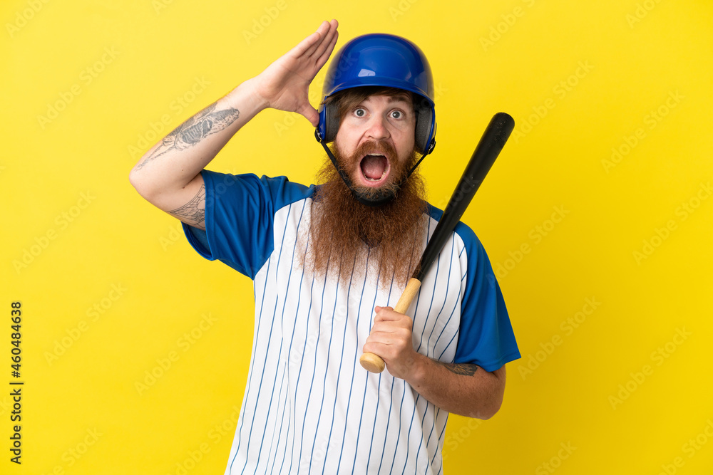 Redhead baseball player man with helmet and bat isolated on yellow background with surprise expression Redhead baseball player man with helmet and bat isolated on yellow background with surprise expression