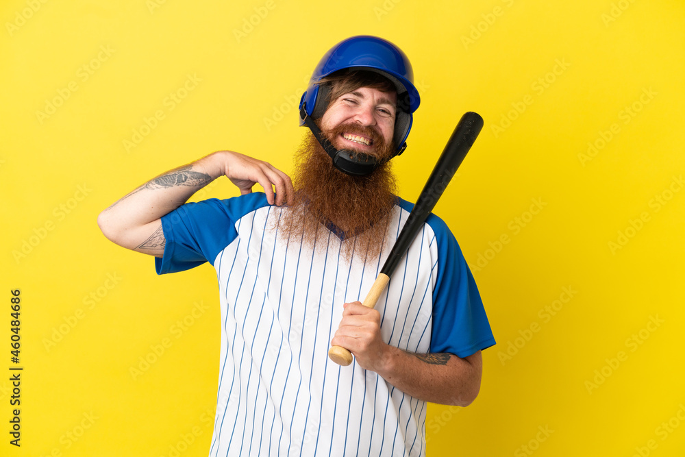 Redhead baseball player man with helmet and bat isolated on yellow background laughing Redhead baseball player man with helmet and bat isolated on yellow background laughing