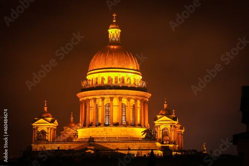 View of the majestic golden dome and colonnade of St. Isaac's Cathedral, illuminated at night, in St. Petersburg.