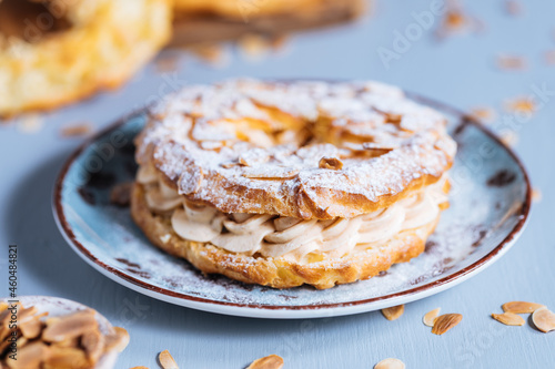 Photography Dessert called Paris Brest on a grey background with powder sugar and almond lea