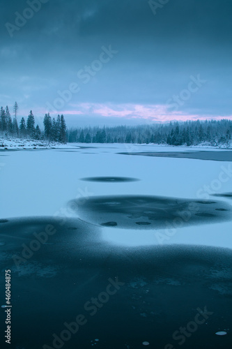 Wonderful natural morning scene of a frozen lake in the white winter mountains with dramatic clouds and weather. Oderteich, Harz Mountains National Park in Germany
