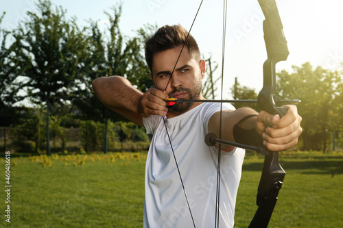 Slika na platnu Man with bow and arrow practicing archery in park