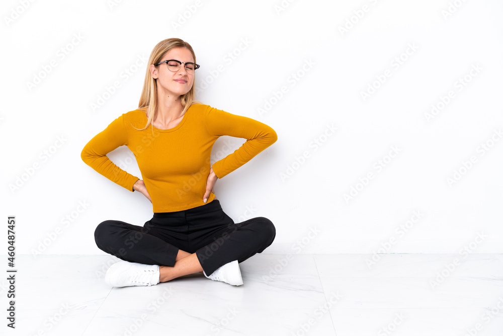 Blonde Uruguayan girl sitting on the floor suffering from backache for having made an effort Blonde Uruguayan girl sitting on the floor suffering from backache for having made an effort