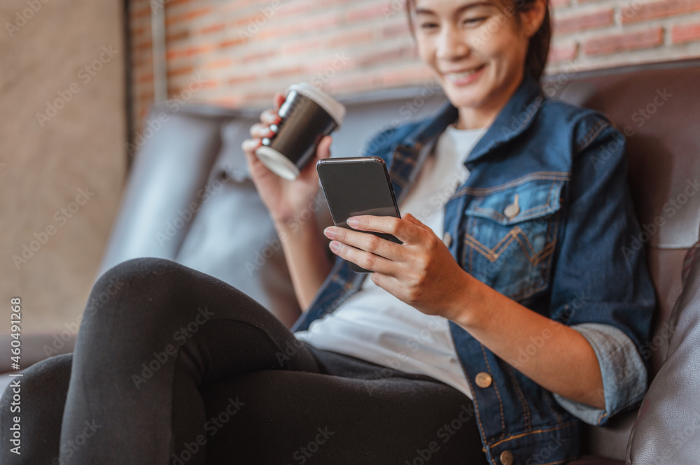 Women hold coffee cup is relax to the watching or shopping on labtop during coffe break after work outside at coffee shop in sunset.