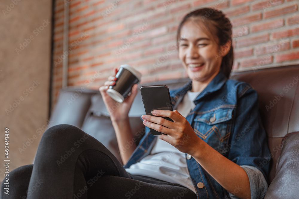 Women hold coffee cup is relax to the watching or shopping on labtop during coffe break after work outside at coffee shop in sunset.