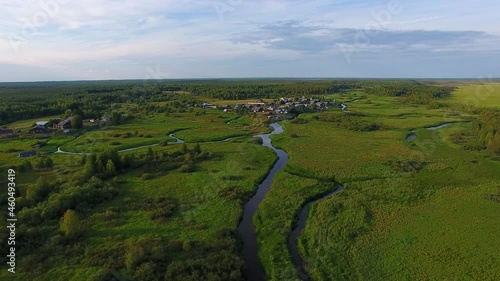 Flying over a Small River.	The camera flies on a small river towards the village. The village is also small, there is a forest behind the village