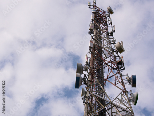 Telecommunication tower antenna with cloud sky as background photo