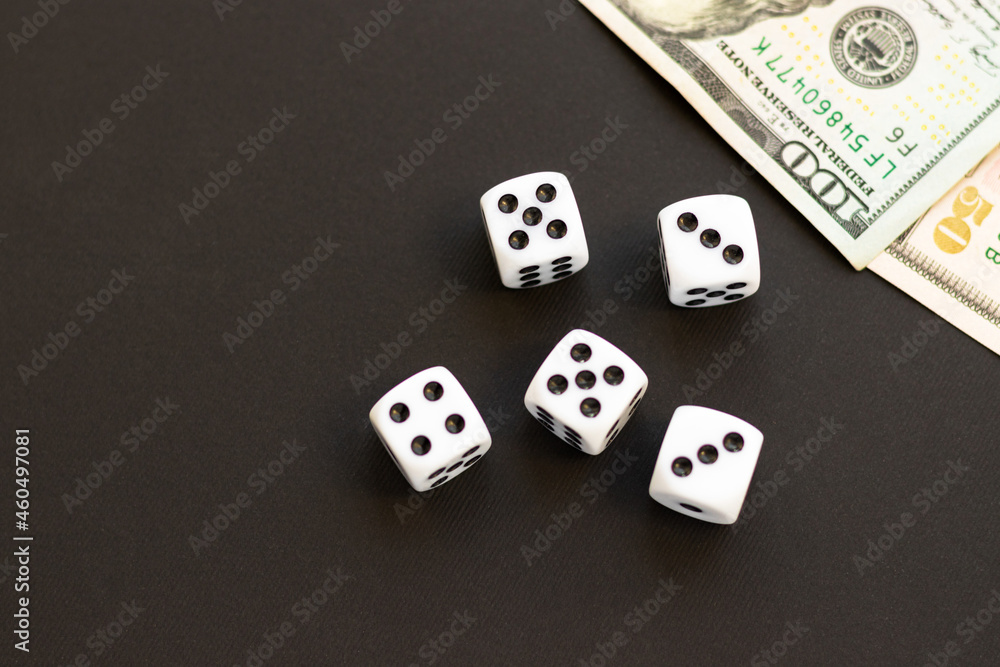 Dice and blurred 100, 50 US dollar on black. Fortune, gaming addiction. Playing cube with numbers. Items for board games. Flat lay, top view, copy space. Dice and blurred 100, 50 US dollar on black. Fortune, gaming addiction. Playing cube with numbers. Items for board games. Flat lay, top view, copy space.