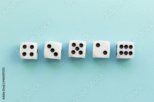 Gaming dice on blue background. Playing cube with numbers. Items for board games. Flat lay  top view with copy space.