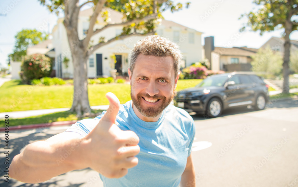 Naklejka premium emotional mature guy gesturing. happy man outdoor on new house background.