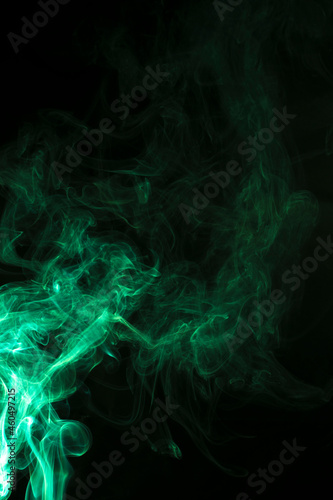 The movement of green smoke takes place on a fierce black background, fearing an abstraction on a black background.