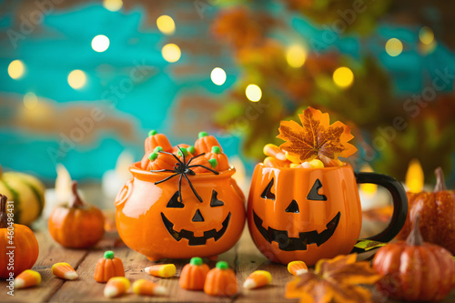 Halloween celebration concept with jack o lantern cup, candy corn and autumn leaves.