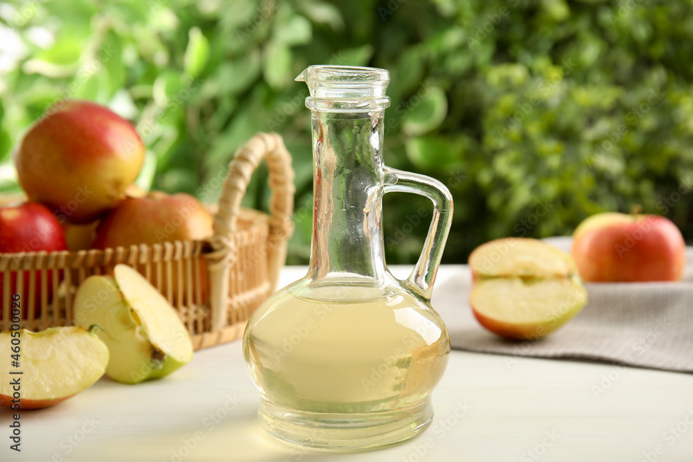 Natural apple vinegar and fresh fruits on white table against blurred background Natural apple vinegar and fresh fruits on white table against blurred background