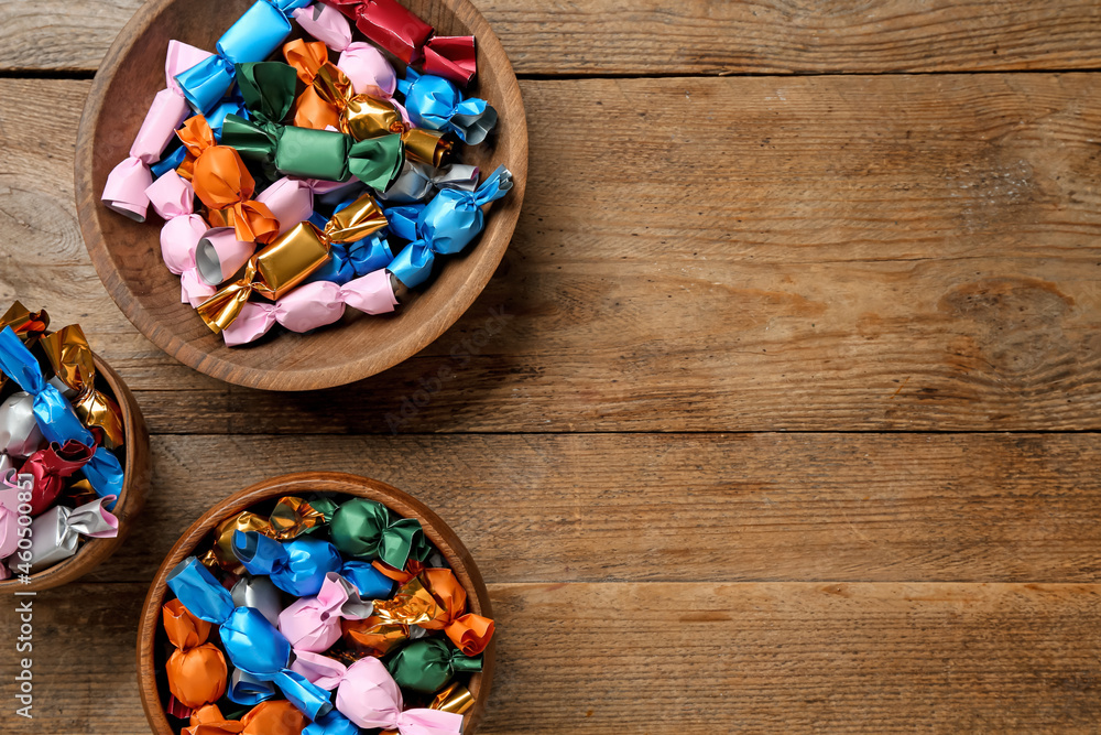 Candies in colorful wrappers on wooden table, flat lay. Space for text Candies in colorful wrappers on wooden table, flat lay. Space for text